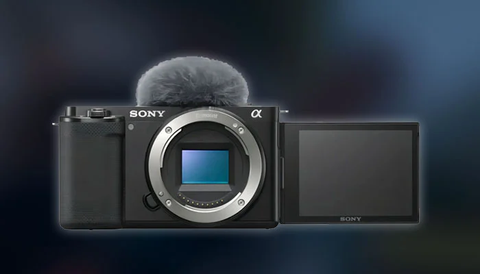 Câmera Sony ZV-E10 preta com a tela articulada virada para frente e microfone com deadcat, ideal para vlogs.